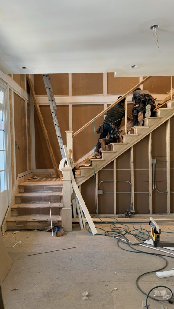 Progress phase of foyer transformation highlighting new flooring, paint, and moldings being installed.