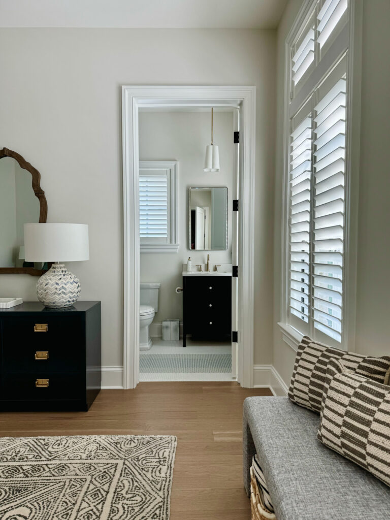 Completed guest bathroom viewed from guest bedroom, featuring a finished vanity, hardwood flooring, stylish tile, modern fixtures, elegant decor, and a cozy ambiance. Perfect for interior design inspiration.