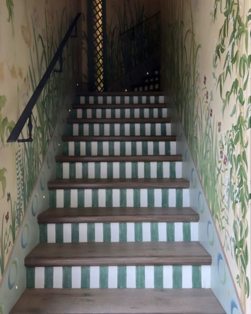 Close-up of staircase featuring white and green striped risers with floral print wallpaper, part of MMDH HQ home project updates.